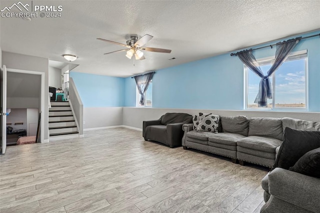 living room with light hardwood / wood-style flooring, ceiling fan, and a textured ceiling