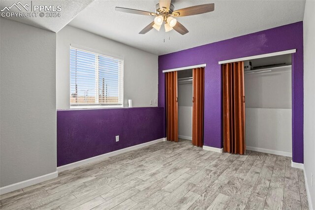 unfurnished bedroom featuring ceiling fan, multiple closets, and light hardwood / wood-style flooring