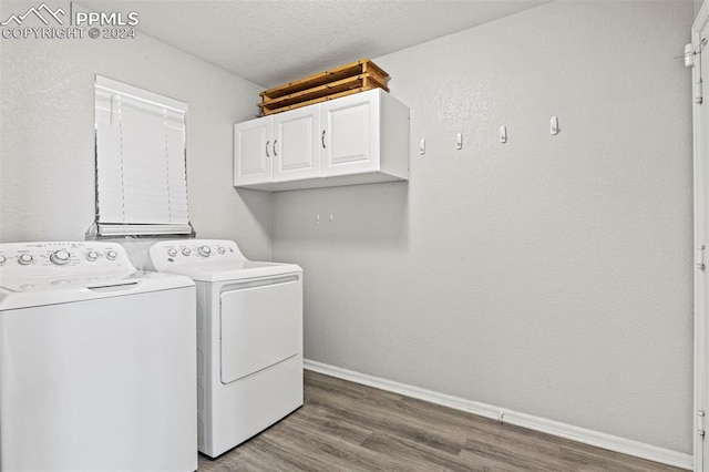 laundry room with cabinets, hardwood / wood-style floors, a textured ceiling, and washer and dryer