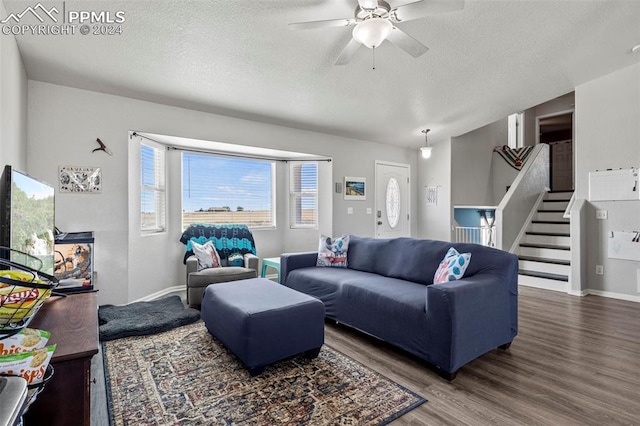 living room with ceiling fan, a textured ceiling, and dark wood-type flooring