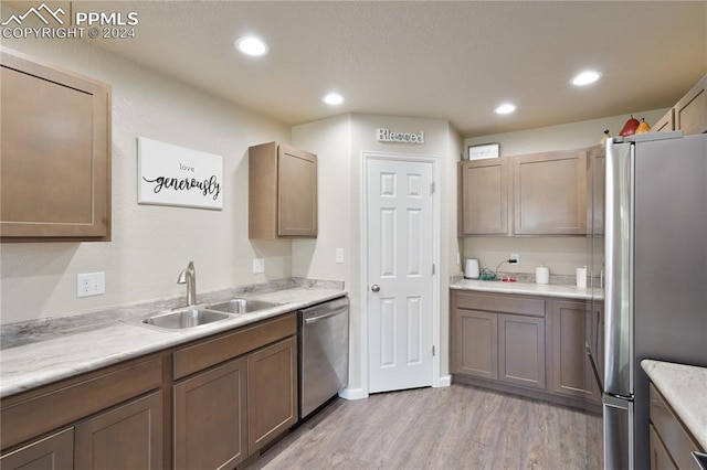 kitchen featuring stainless steel appliances, light wood-type flooring, and sink