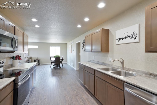 kitchen featuring a textured ceiling, light hardwood / wood-style floors, appliances with stainless steel finishes, and sink