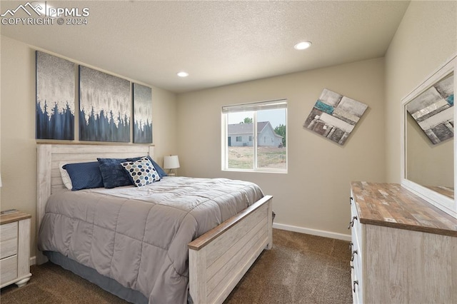 bedroom with dark carpet and a textured ceiling