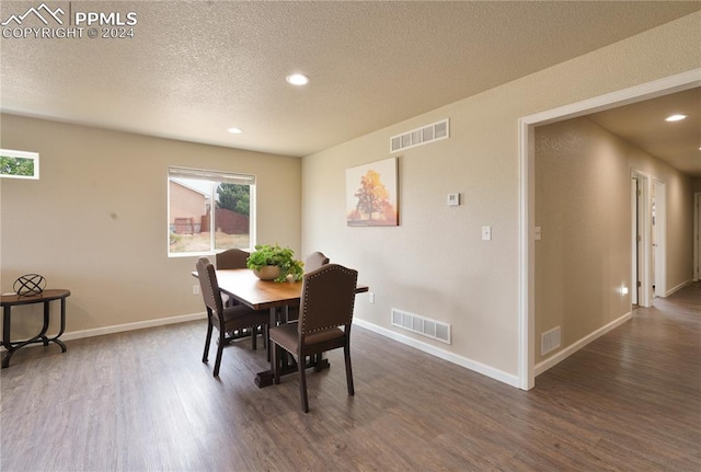 dining space with a textured ceiling and dark hardwood / wood-style flooring