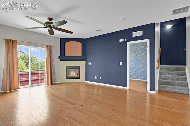 unfurnished living room featuring a tile fireplace, ceiling fan, and light hardwood / wood-style flooring