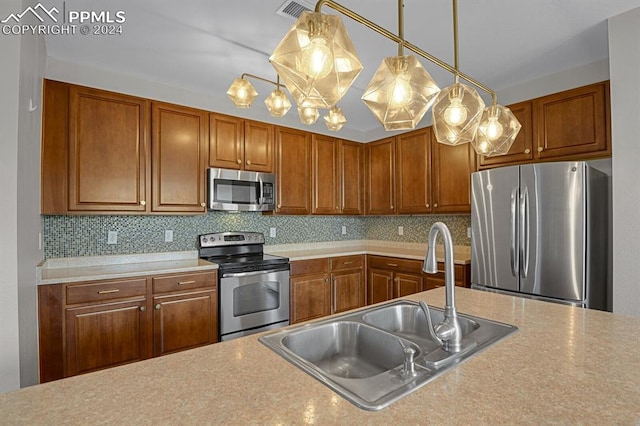 kitchen featuring pendant lighting, appliances with stainless steel finishes, sink, and decorative backsplash