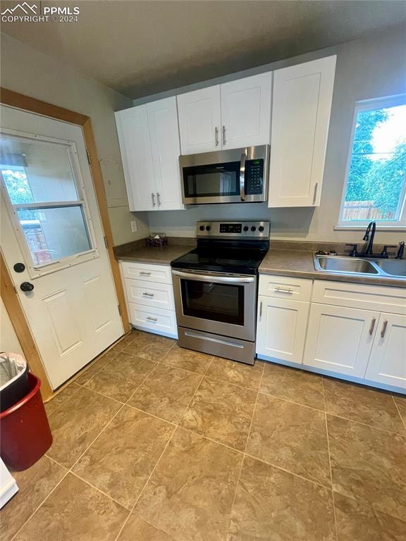 kitchen featuring appliances with stainless steel finishes, sink, and white cabinetry