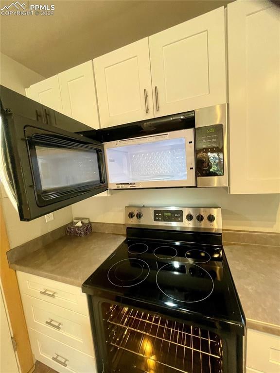 kitchen featuring stainless steel electric stove and white cabinetry