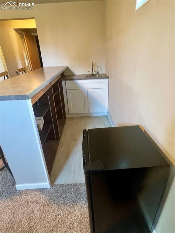 kitchen featuring white cabinets, light hardwood / wood-style floors, and sink