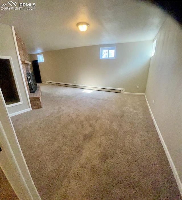 basement featuring a textured ceiling, carpet flooring, baseboard heating, and a brick fireplace