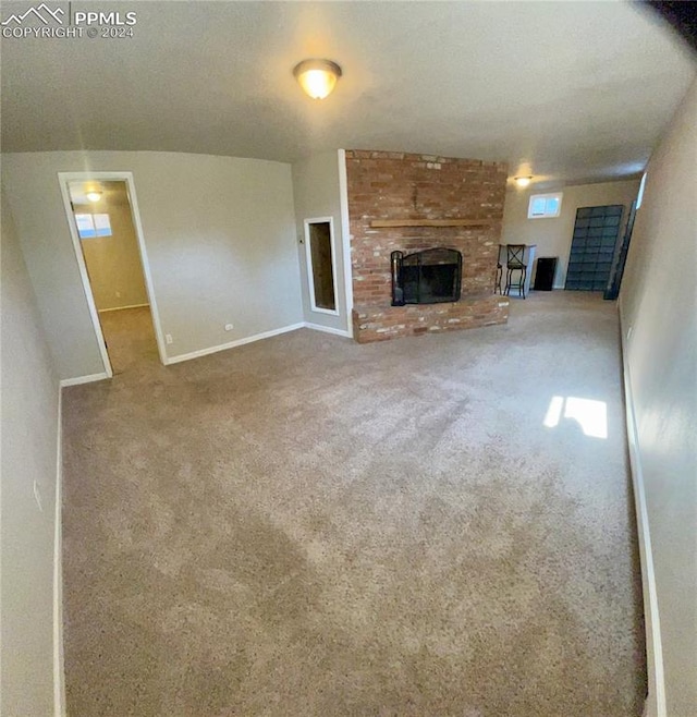 unfurnished living room featuring a brick fireplace and carpet flooring