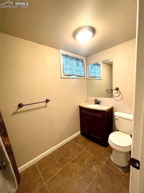 bathroom featuring tile patterned flooring, a textured ceiling, vanity, and toilet