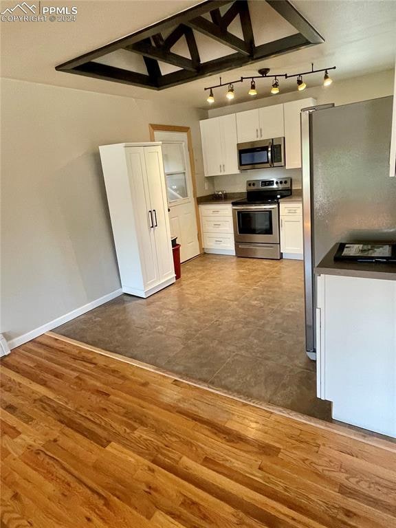 kitchen with dark hardwood / wood-style floors, stainless steel appliances, and white cabinets