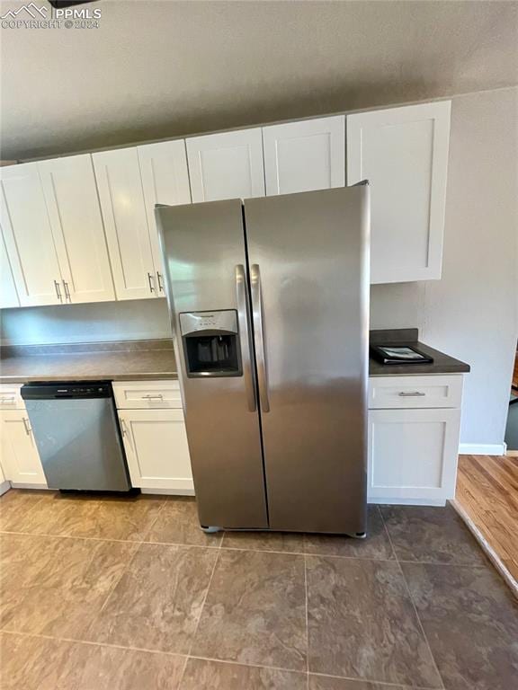 kitchen with appliances with stainless steel finishes, light hardwood / wood-style floors, and white cabinets