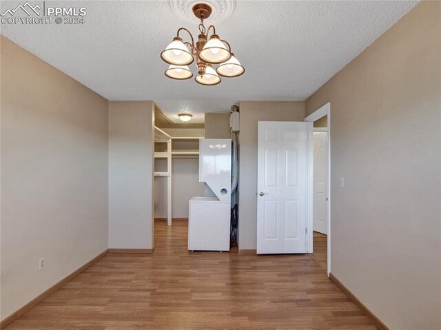 interior space featuring a textured ceiling, an inviting chandelier, and light hardwood / wood-style flooring