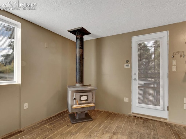 details with hardwood / wood-style flooring, a textured ceiling, and a wood stove