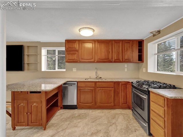 kitchen featuring light stone counters, sink, kitchen peninsula, a textured ceiling, and stainless steel appliances