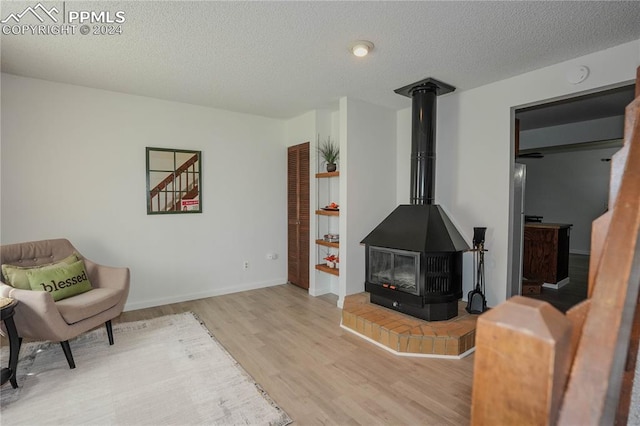 living area featuring a textured ceiling, light wood-type flooring, and a wood stove