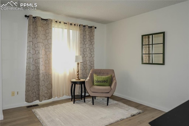 living area featuring a textured ceiling and hardwood / wood-style floors