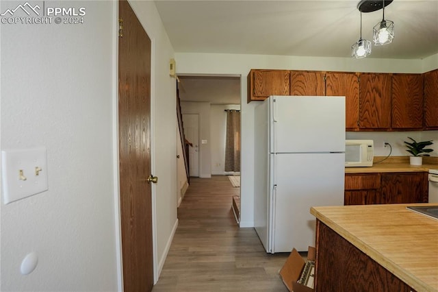 kitchen featuring light wood-type flooring, white appliances, and hanging light fixtures