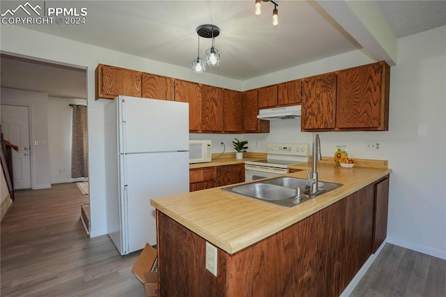 kitchen with light hardwood / wood-style floors, hanging light fixtures, white appliances, and kitchen peninsula