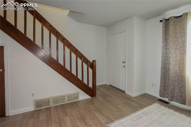 foyer with a textured ceiling and light hardwood / wood-style flooring