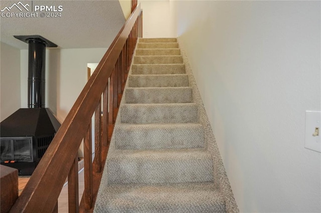 stairs featuring a textured ceiling and a wood stove