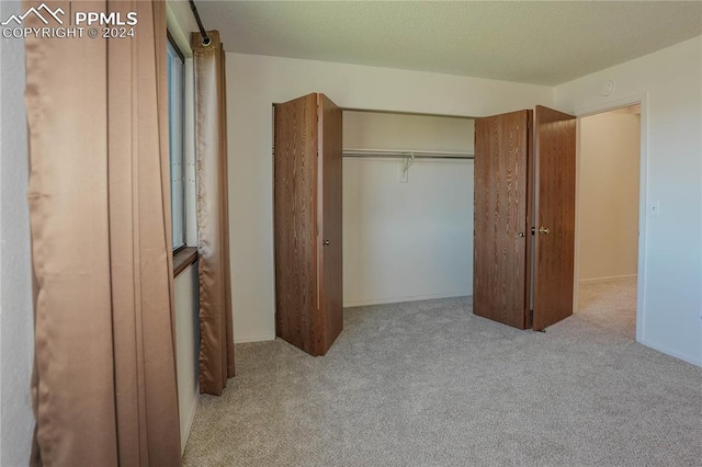 unfurnished bedroom featuring a closet and light colored carpet