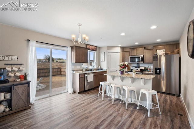 kitchen with decorative light fixtures, appliances with stainless steel finishes, dark hardwood / wood-style floors, and a center island