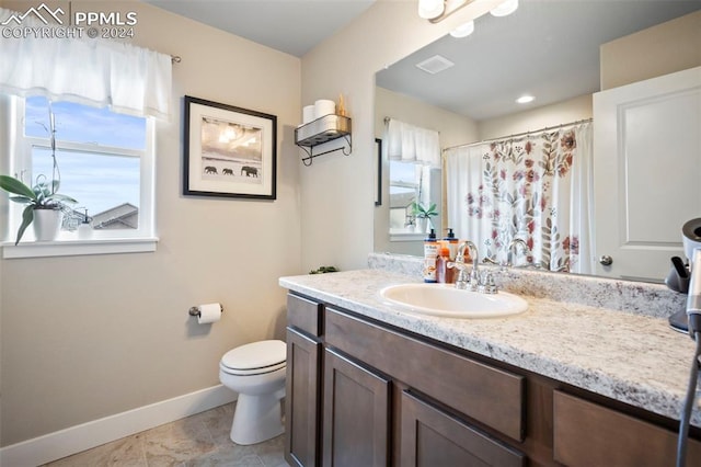 bathroom featuring a healthy amount of sunlight, vanity, and toilet