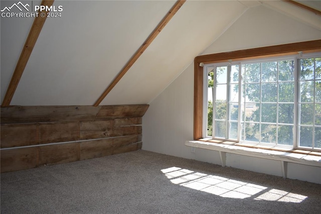 bonus room with carpet floors and vaulted ceiling with beams