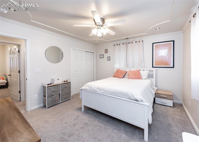 carpeted bedroom with ornamental molding, ceiling fan, and a closet