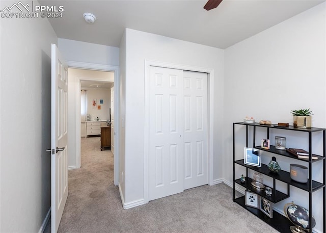 bedroom featuring light colored carpet, ceiling fan, and a closet