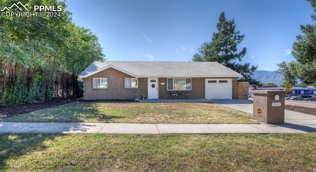 ranch-style home featuring a garage, a mountain view, and a front lawn