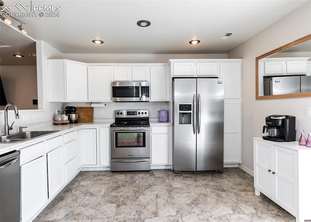 kitchen with appliances with stainless steel finishes, sink, and white cabinets