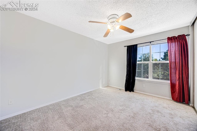 spare room with ceiling fan, light colored carpet, and a textured ceiling