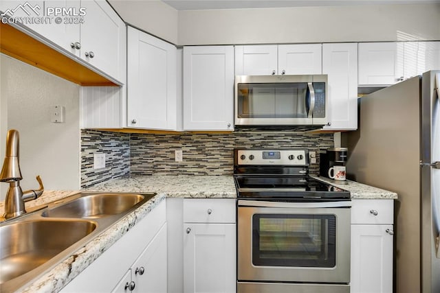 kitchen with appliances with stainless steel finishes, backsplash, sink, and white cabinetry