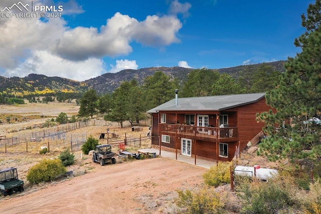 view of front of home featuring a balcony, a mountain view, and a rural view