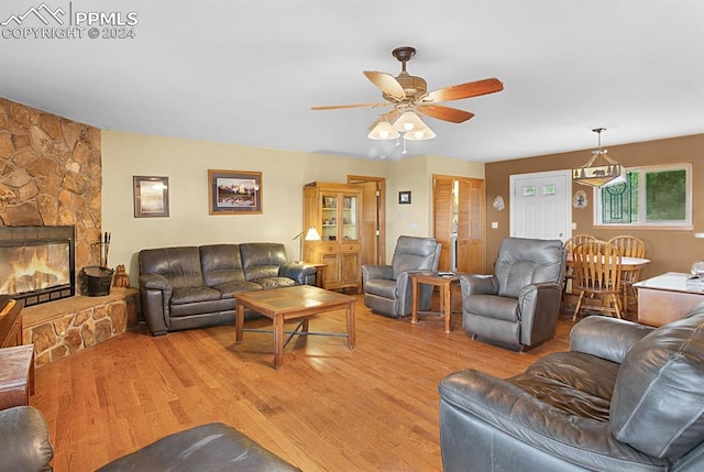 living room featuring light wood-type flooring, ceiling fan, and a fireplace