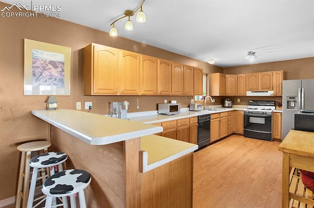 kitchen with light wood-type flooring, sink, a breakfast bar area, kitchen peninsula, and white appliances