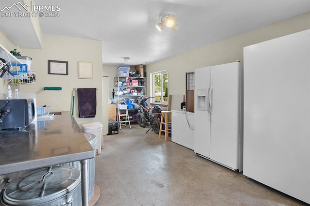 interior space featuring white refrigerator with ice dispenser and washer / dryer