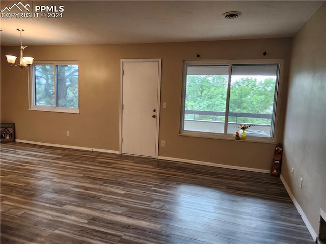 empty room with an inviting chandelier and dark hardwood / wood-style floors