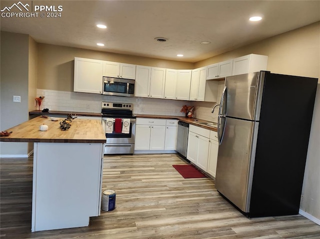 kitchen with light wood-type flooring, butcher block countertops, stainless steel appliances, and white cabinetry