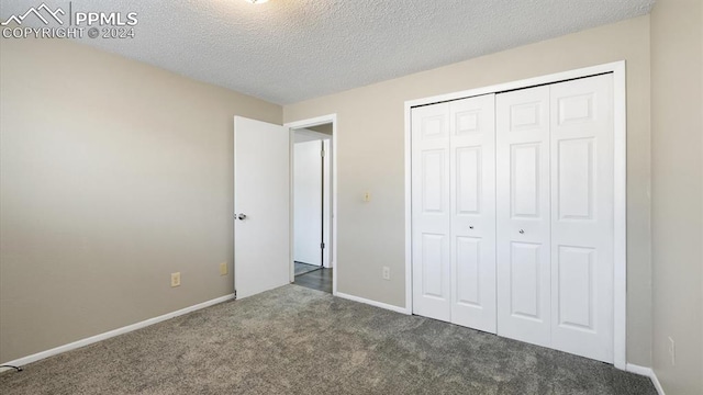 unfurnished bedroom featuring a textured ceiling, a closet, and dark colored carpet