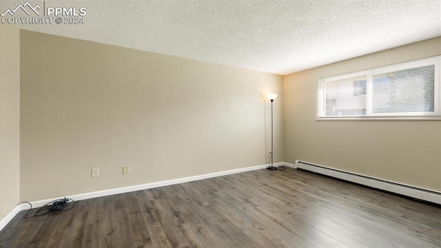 unfurnished room featuring a textured ceiling, baseboard heating, and hardwood / wood-style floors