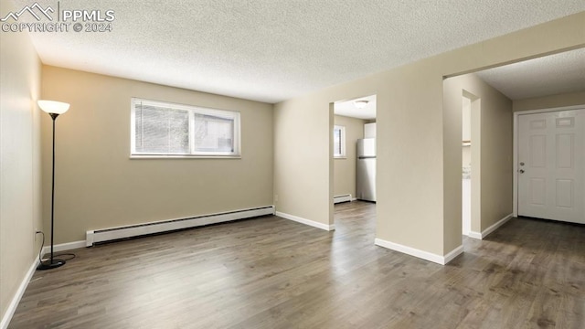 spare room featuring a baseboard radiator, a textured ceiling, and hardwood / wood-style flooring