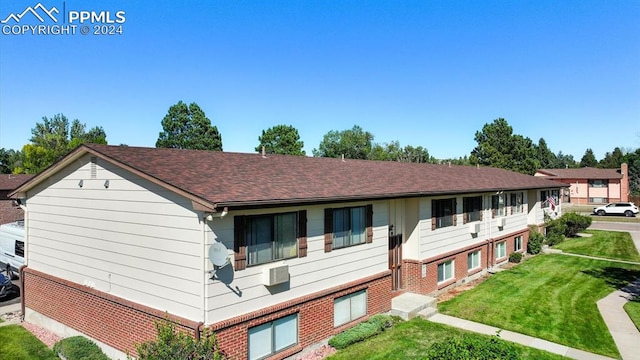 view of front of home with a wall mounted air conditioner and a front lawn