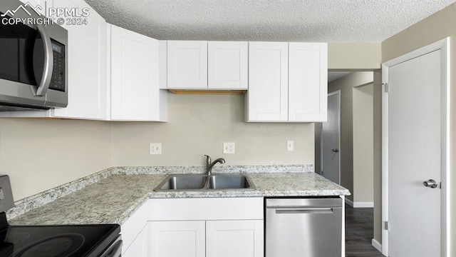 kitchen featuring white cabinets, a textured ceiling, appliances with stainless steel finishes, and sink