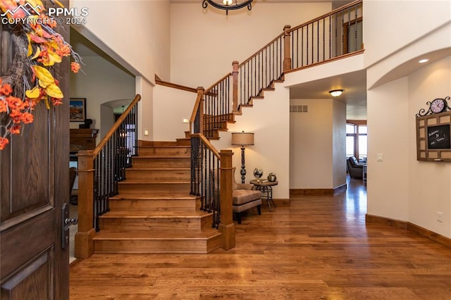 staircase with a towering ceiling and hardwood / wood-style floors