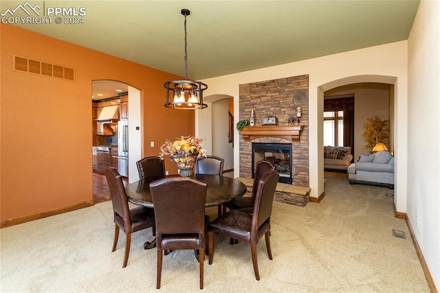 carpeted dining space featuring a stone fireplace